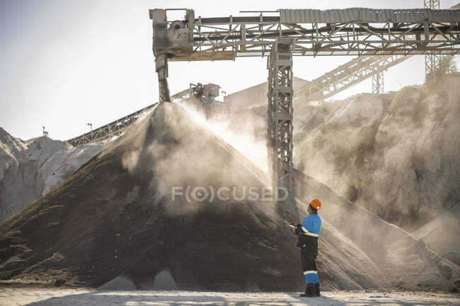 Steinbrucharbeiter steht neben Aggregathaufen im Steinbruch — Stockfoto