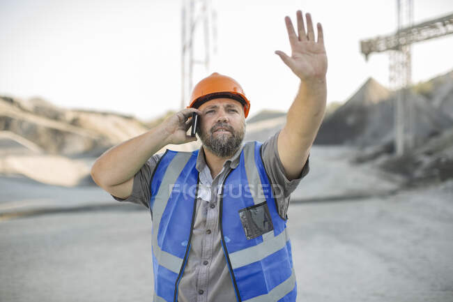 Pedreira trabalhador na pedreira, usando smartphone, gesticulando com a mão — Fotografia de Stock