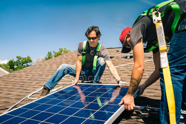 Dos obreros instalando paneles solares en el techo de la casa - foto de stock