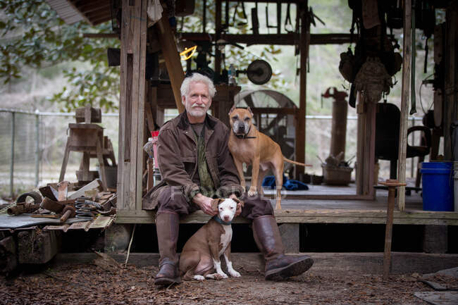 Homem com cães de estimação por cabana de trabalho de madeira — Fotografia de Stock