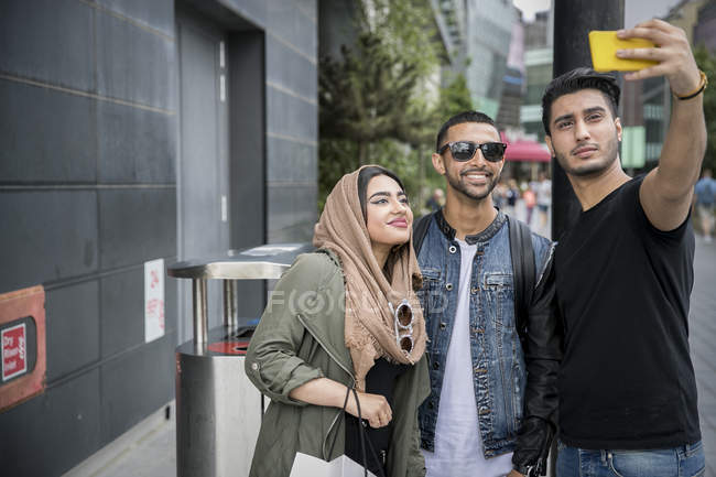 Three friends in street taking selfie with smartphone — Stock Photo