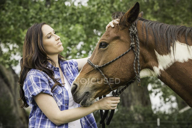 Portrait of young woman, petting horse — Stock Photo