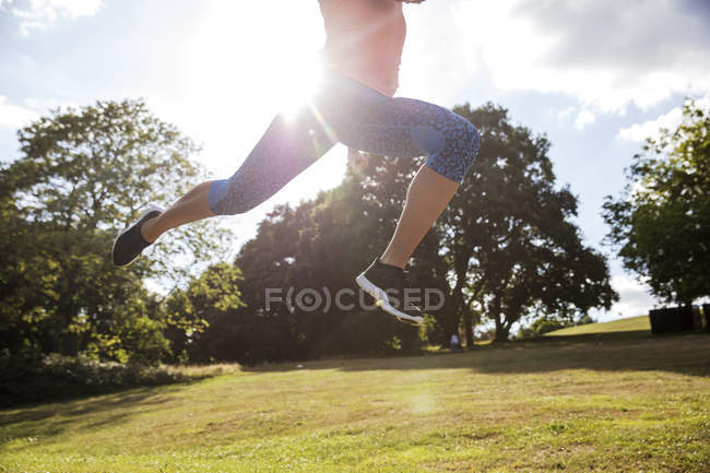 Mujer joven saltando en el aire y entrenando en el parque - foto de stock