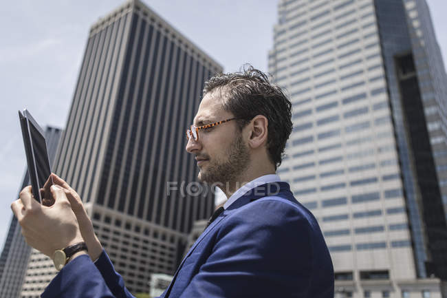 Молодой бизнесмен смотрит на цифровой планшет на открытом воздухе — стоковое фото