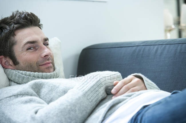 Portrait of mid adult man looking sideways while lying on sofa — Stock Photo