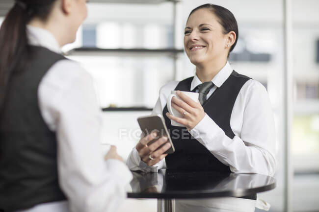 Dos camareras en el restaurante, tomando un descanso, hablando - foto de stock