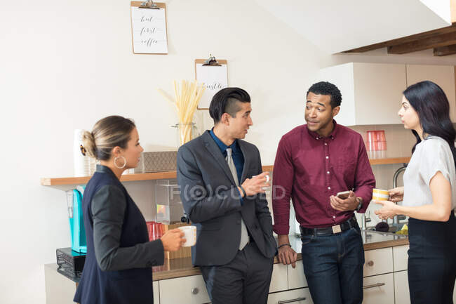 Businesswomen and men having informal meeting in office kitchen — Stock Photo