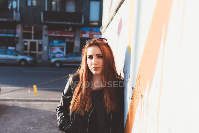 Portrait of red haired woman leaning against wall — Stock Photo