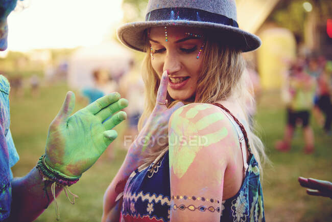 Junge Frau mit grünem Handabdruck auf Schulter und Freund kreidete Hand auf Festival — Stockfoto