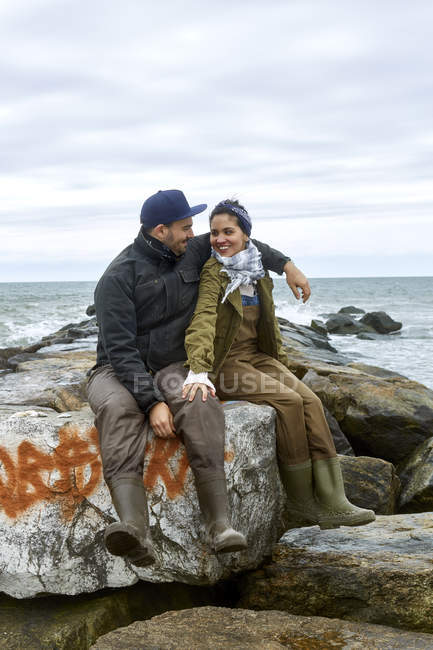 Jovem casal de pescadores sentado em rochas de praia — Fotografia de Stock