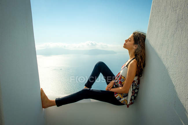Ragazza seduta sul balcone con il mare sullo sfondo, Santorini, Kikladhes, Grecia — Foto stock
