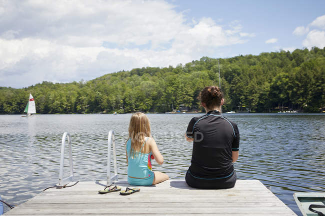 Two young girls sitting on jetty — Stock Photo