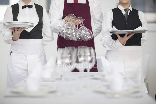 Waiting staff in restaurant preparing table, mid section — Stock Photo