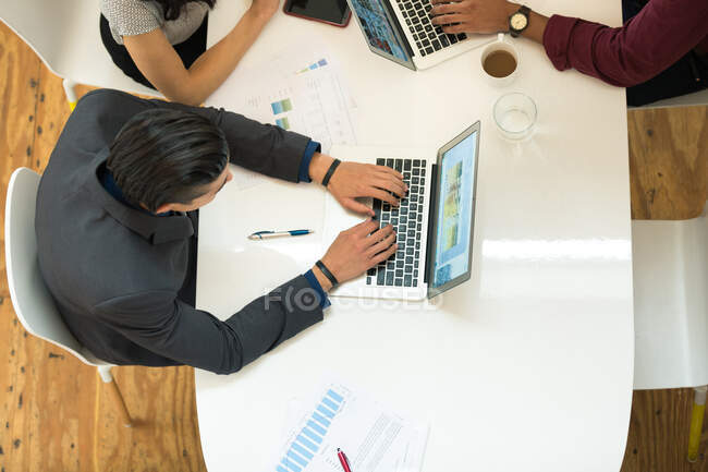 Vista aérea del hombre de negocios escribiendo en el ordenador portátil en la mesa de la oficina - foto de stock