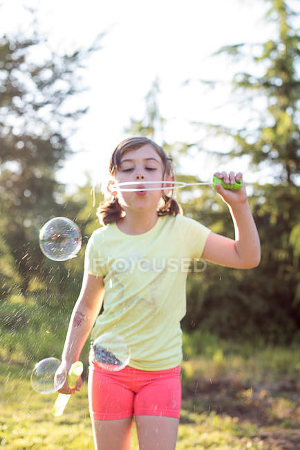 Young girl blowing soap bubbles outdoors — Stock Photo