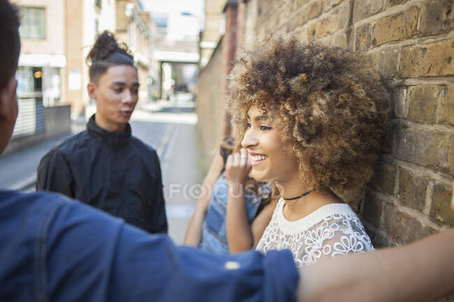 Four friends standing in street, talking, smiling — Stock Photo