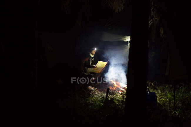 Deux hommes assis près d'un feu de camp, regardant la carte — Photo de stock