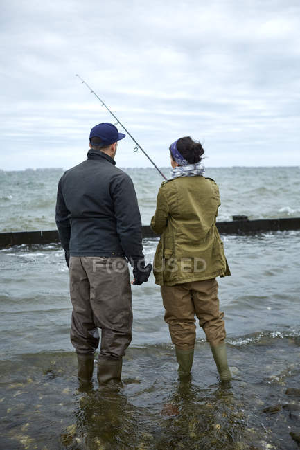 Vista trasera del joven enseñando pesca novia - foto de stock