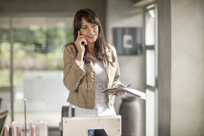 Mature woman working from home making smartphone call in living room — Stock Photo
