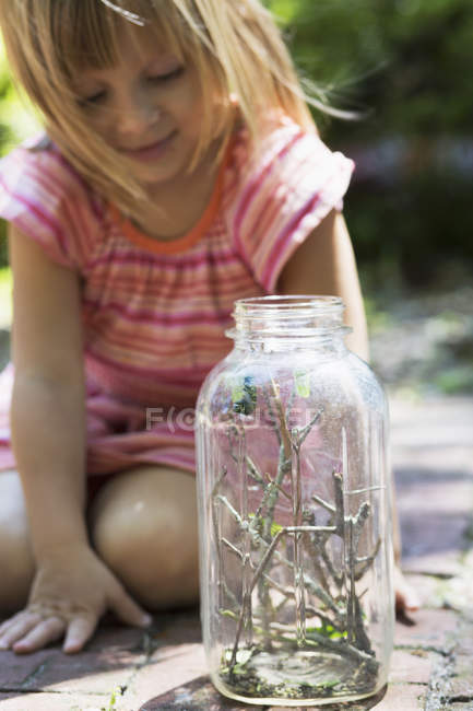 Menina olhando para lagarta em frasco — Fotografia de Stock