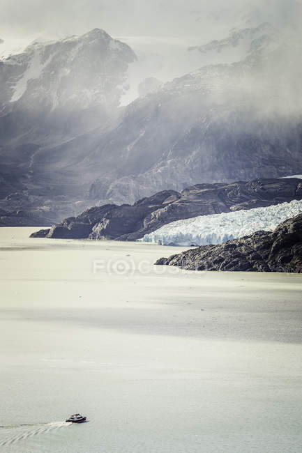Barca a vela sul Lago Grigio, con nuvole basse sulle montagne, Parco nazionale Torres del Paine, Cile — Foto stock