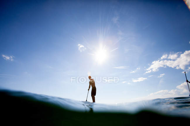 Young man paddle boarding, surface level view — Stock Photo