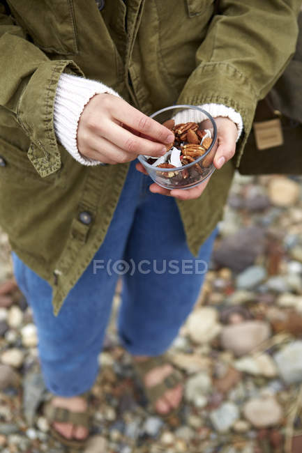 Жінка на гальковому пляжі тримає свіжі горіхи — стокове фото