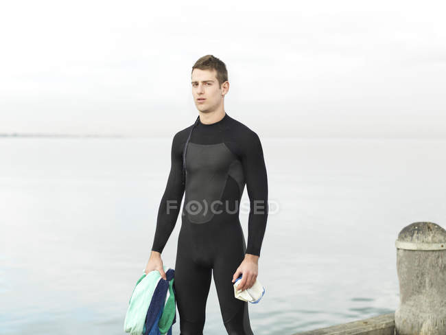 Hombre por mar en traje mojado mirando a la cámara, Melbourne, Victoria, Australia, Oceanía - foto de stock