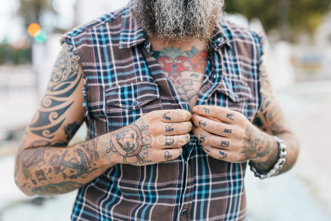 Tattooed male hipster fastening shirt buttons, cropped — Stock Photo