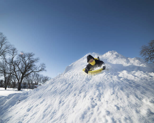 Мальчик катается на санках по снегу — стоковое фото