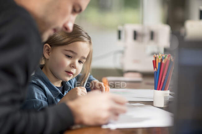 Jeune homme et sa fille dessinent à table — Photo de stock