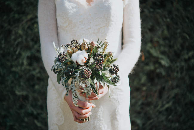 Bride with wedding bouquet with hedge at background — Stock Photo