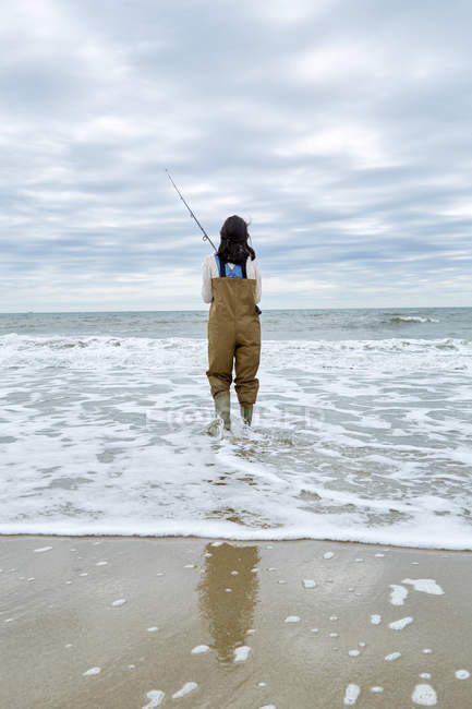 Jeune femme dans les échassiers pêche en mer — Photo de stock