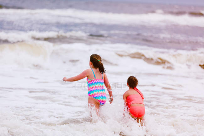 Две девочки, играющие на океанских волнах, остров Дофин, Алабама, США — стоковое фото