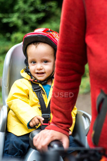 Woman walking with bicycle, young son sitting in child's seat of bike, mid section — Stock Photo