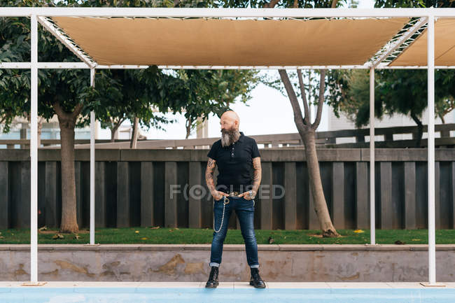 Mature male hipster standing below canopy with hands in pockets — Stock Photo