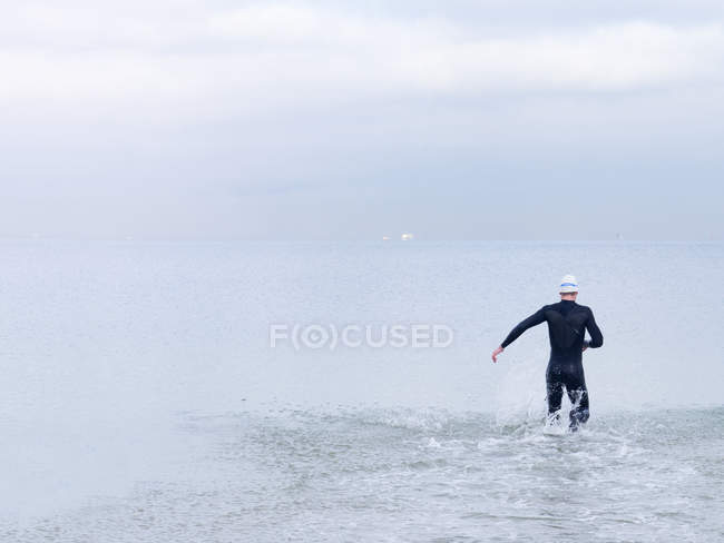 Rear view of man in wet suit and swimming cap in sea, Melbourne, Victoria, Australia, Oceania — Stock Photo