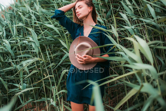 Mujer al lado de hierba larga tocando el pelo - foto de stock