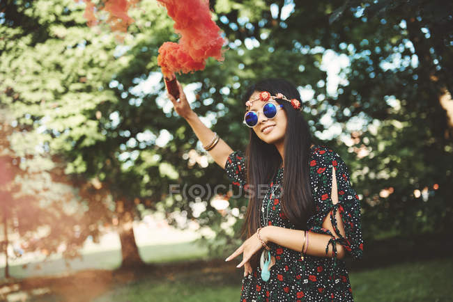 Mujer joven sosteniendo bengala de humo rojo - foto de stock