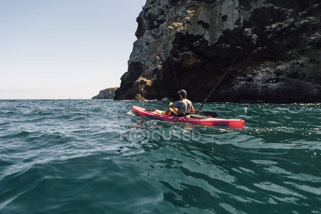 Jovem macho mar kayaker pesca perto de penhasco, Ilha de Santa Cruz, Califórnia, EUA — Fotografia de Stock
