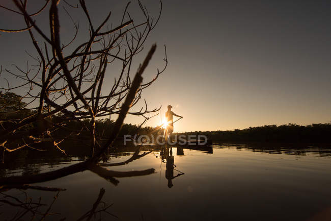 Mann paddelt bei Sonnenuntergang auf dem Wasser — Stockfoto