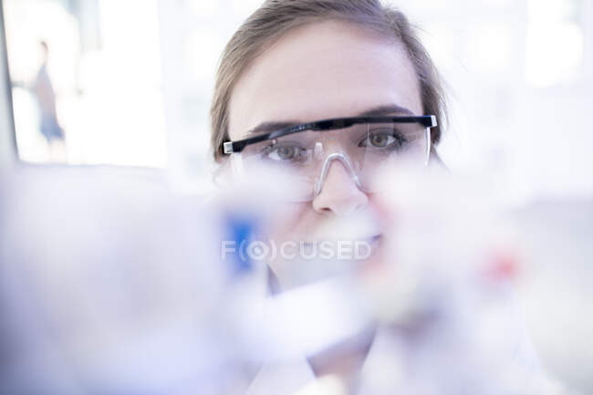 Працівник лабораторії дивиться на лабораторне обладнання — стокове фото
