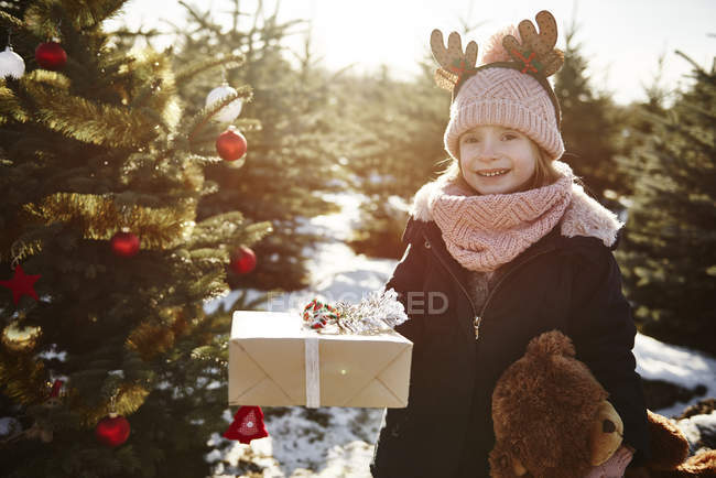 Girl in christmas tree forest wearing antlers, portrait — Stock Photo