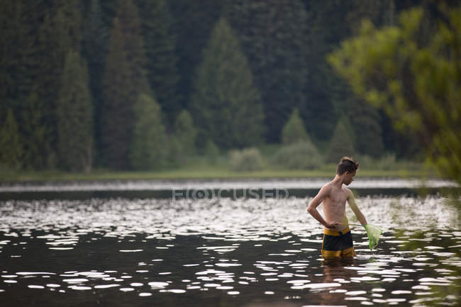 Vue lointaine de adolescent garçon pêche à l'aide de filet — Photo de stock