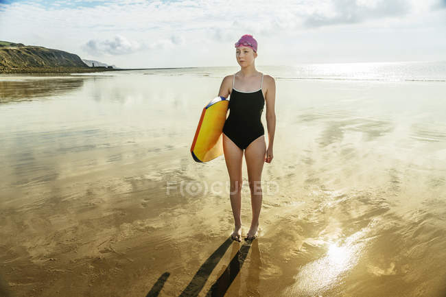Young woman carrying surfboard on beach — Stock Photo