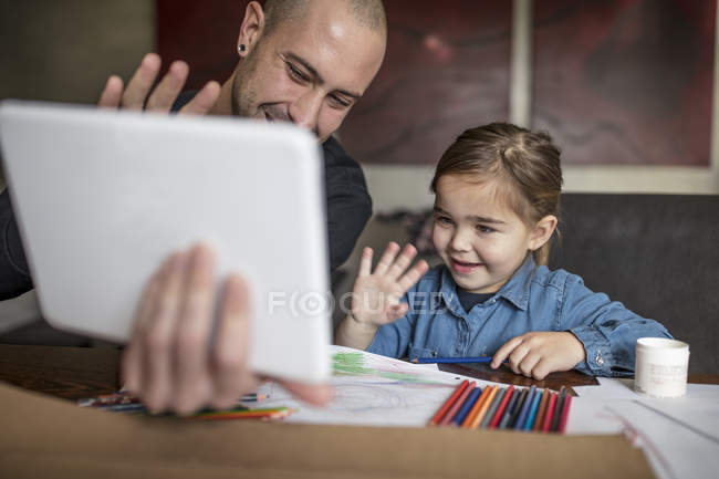 Hombre e hija saludando a la tableta digital - foto de stock