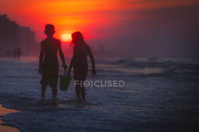 Siblings paddling in sea at sunset, North Myrtle Beach, South Carolina, United States — Stock Photo
