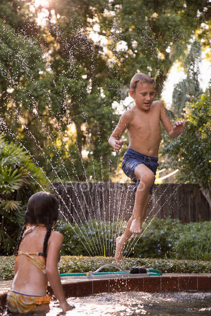 Молодий хлопчик стрибає в садовий басейн — стокове фото