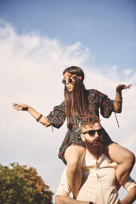 Young boho woman dancing on boyfriend's shoulders at festival — Stock Photo