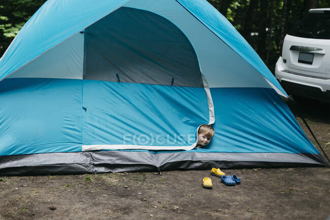 Retrato de tiro na cabeça da criança do sexo masculino bonito espreitando da barraca azul, Huntsville, Canadá — Fotografia de Stock